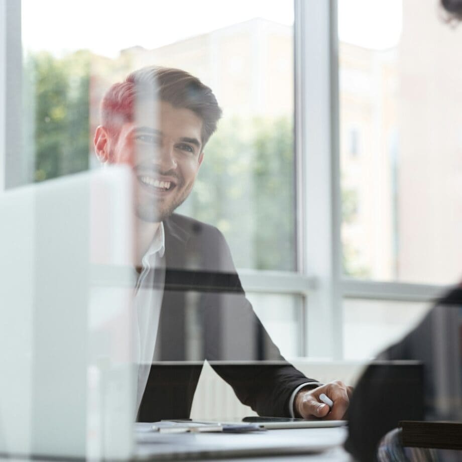 Two cheerful young businessmen with laptop on business meeting